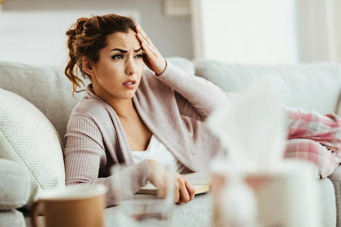 Femme épuisée sur un canapé, la main sur le front : fatigue liée à une anémie causée par un fibrome utérin