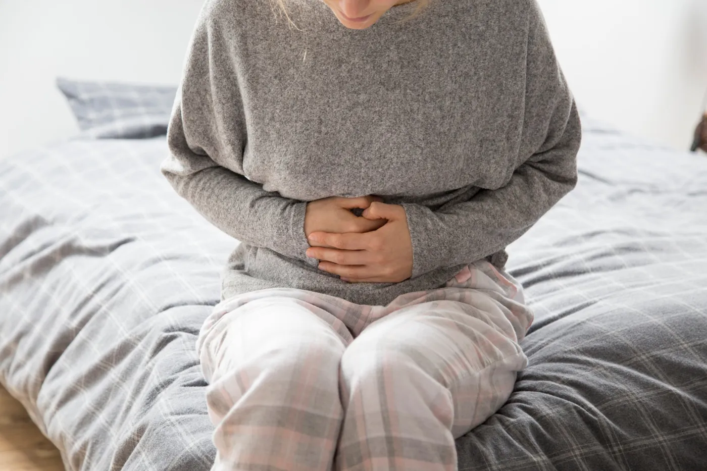 Femme se tenant le ventre : constipation et gêne abdominale liées à un fibrome utérin